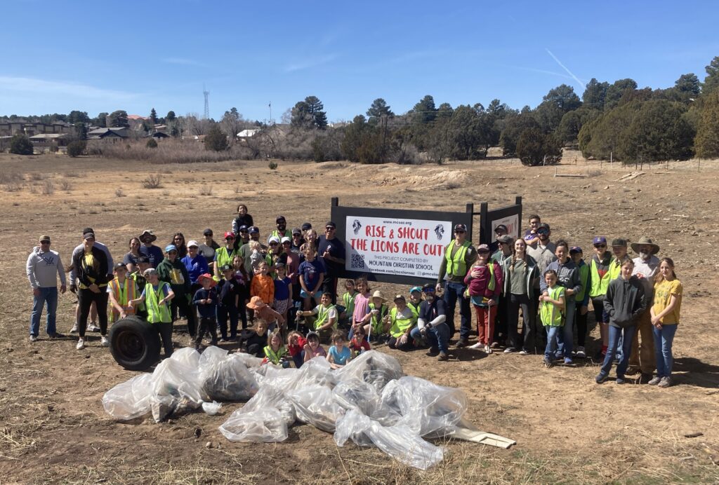 Clean-Up Day 2025 Nearly 50 volunteers with trash bags collect debris in the open field which will soon be playground at a new park in Show Low Arizona. It was a beautiful, sunny day with bright blue skies and a gentle breeze.